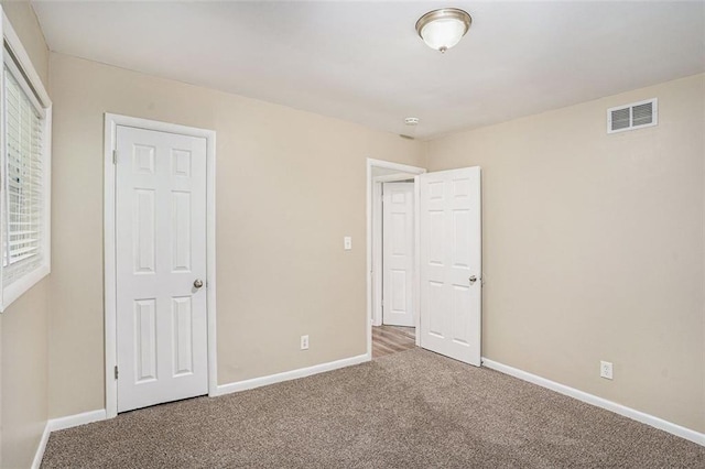 unfurnished bedroom featuring carpet floors, baseboards, and visible vents