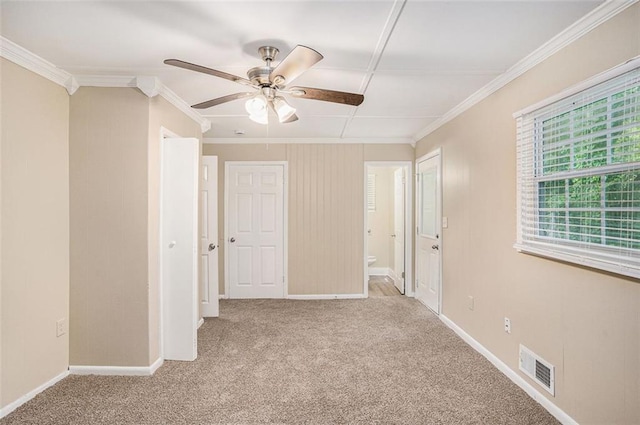 carpeted spare room with crown molding, a ceiling fan, baseboards, and visible vents