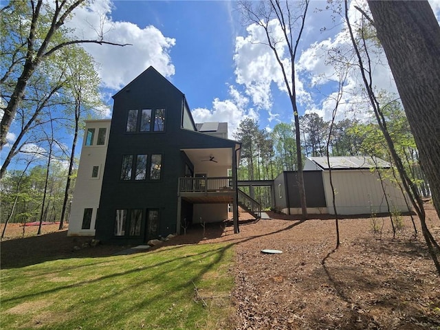 back of house featuring a ceiling fan, a lawn, a wooden deck, and stairway