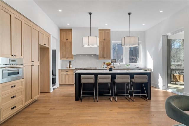 kitchen featuring appliances with stainless steel finishes, light brown cabinets, light wood finished floors, and recessed lighting