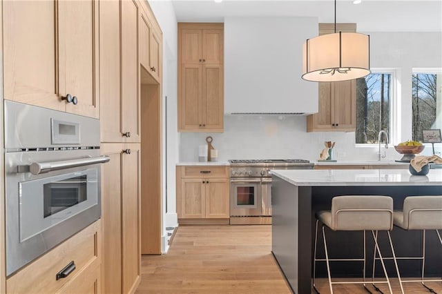kitchen featuring appliances with stainless steel finishes, light brown cabinetry, custom exhaust hood, a sink, and light wood-style floors
