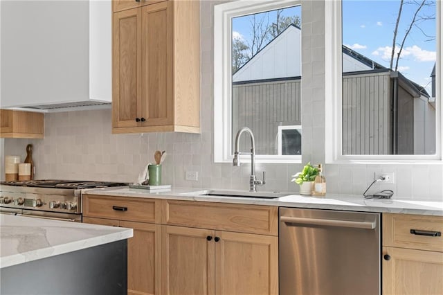 kitchen with stainless steel appliances, wall chimney exhaust hood, a sink, decorative backsplash, and light stone counters