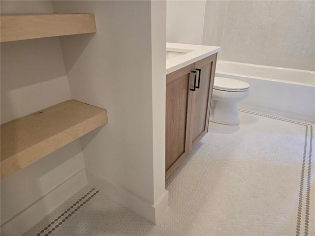 bathroom with vanity, a tub to relax in, and toilet