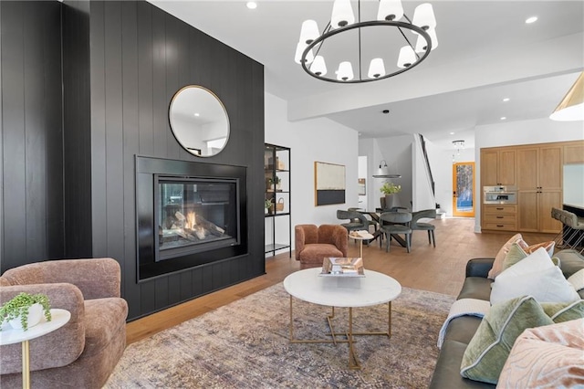 living room featuring a chandelier, wood finished floors, a large fireplace, and recessed lighting