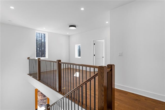 hall featuring an upstairs landing, wood finished floors, recessed lighting, and baseboards