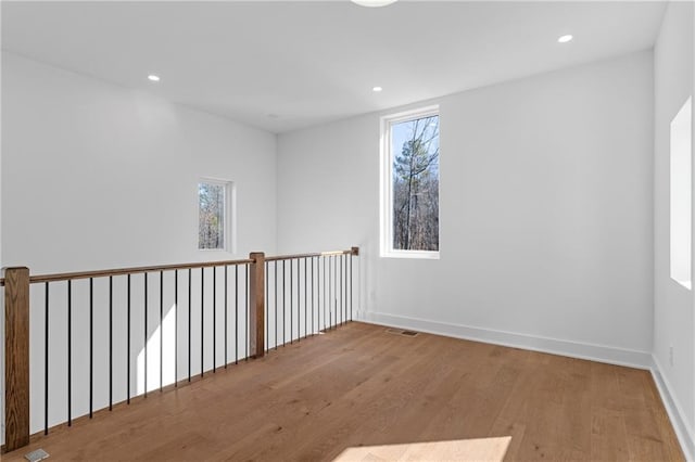 spare room featuring wood finished floors, healthy amount of natural light, recessed lighting, and baseboards