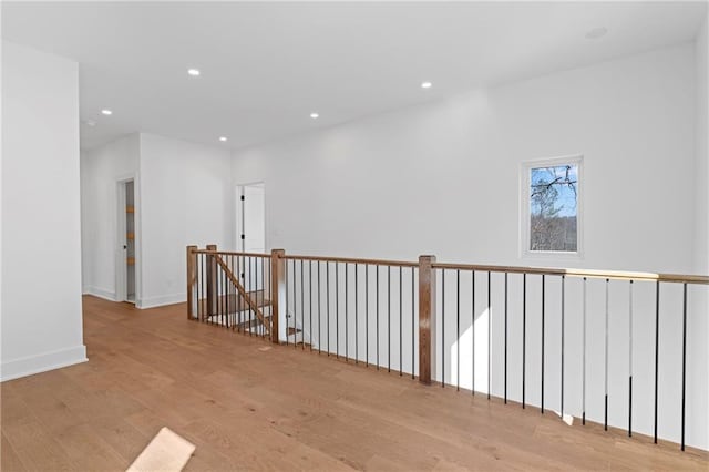 hallway featuring wood finished floors, recessed lighting, baseboards, and an upstairs landing