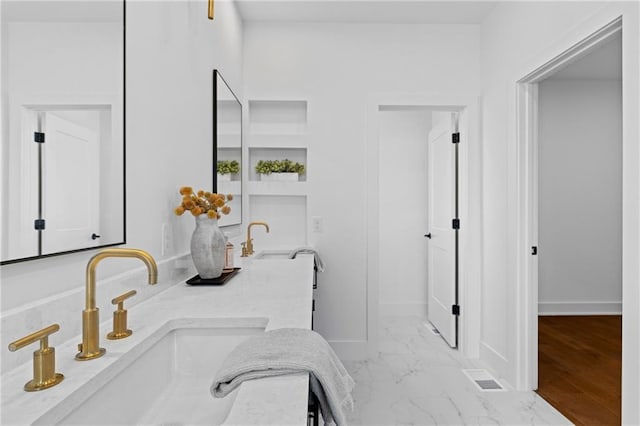 bathroom with baseboards, marble finish floors, and double vanity
