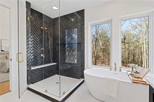 full bathroom with marble tiled flooring, a freestanding tub, a stall shower, and ensuite bath