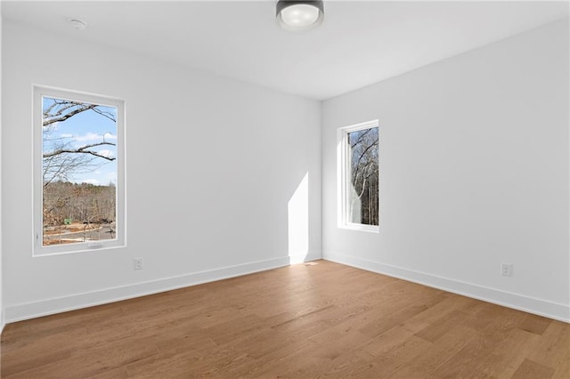 unfurnished room featuring wood finished floors, baseboards, and a smoke detector
