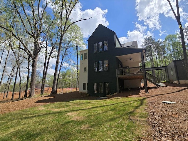 rear view of property with ceiling fan, a lawn, stairway, and a wooden deck