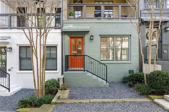 entrance to property featuring a balcony and brick siding