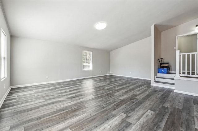 unfurnished living room with stairway, wood finished floors, and baseboards