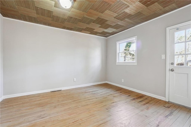 spare room with light wood-type flooring, baseboards, and ornamental molding