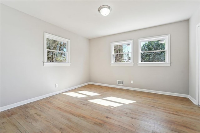 empty room with light wood finished floors, baseboards, and visible vents