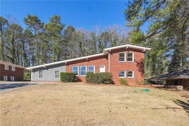 view of front of house with brick siding, driveway, and a front lawn