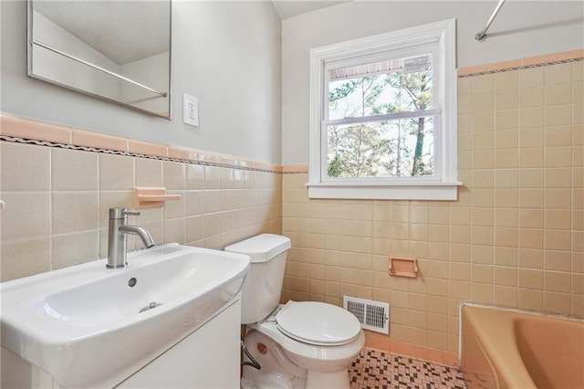 full bath with tile patterned flooring, toilet, vanity, visible vents, and tile walls