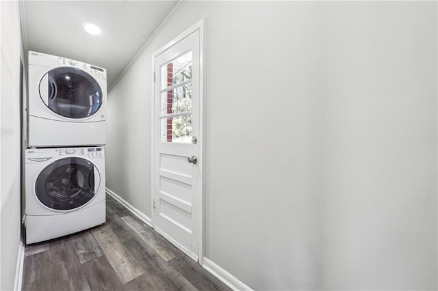 laundry area with dark wood-style flooring, ornamental molding, stacked washer / dryer, laundry area, and baseboards