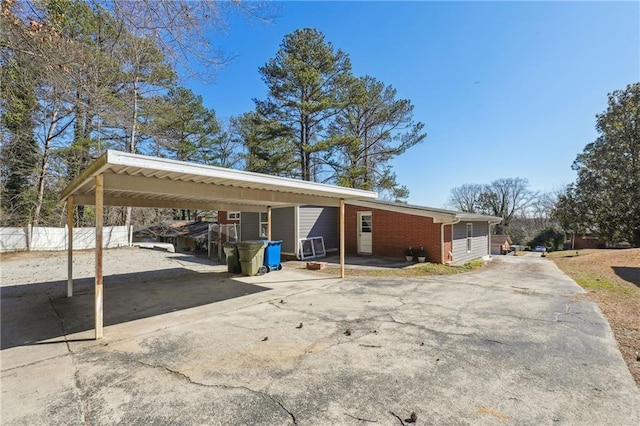 exterior space featuring a carport, brick siding, driveway, and fence