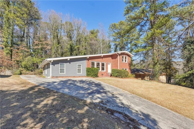 view of front of house featuring concrete driveway, brick siding, crawl space, and a front yard