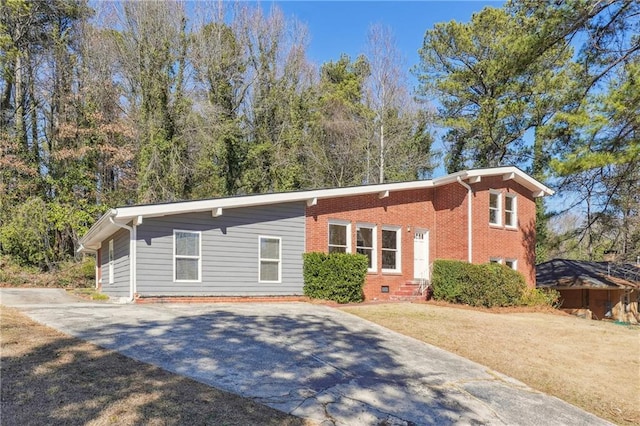 view of front of home with concrete driveway, brick siding, crawl space, and a front yard