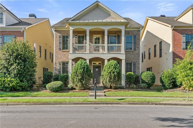 greek revival house featuring brick siding and a balcony