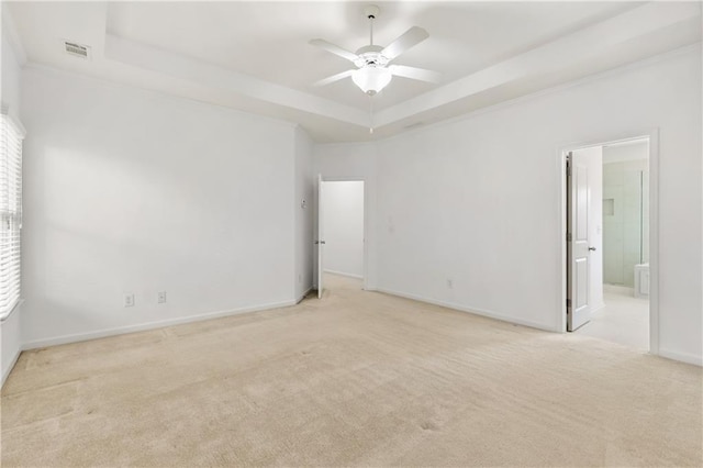 spare room featuring visible vents, baseboards, light colored carpet, ceiling fan, and a tray ceiling