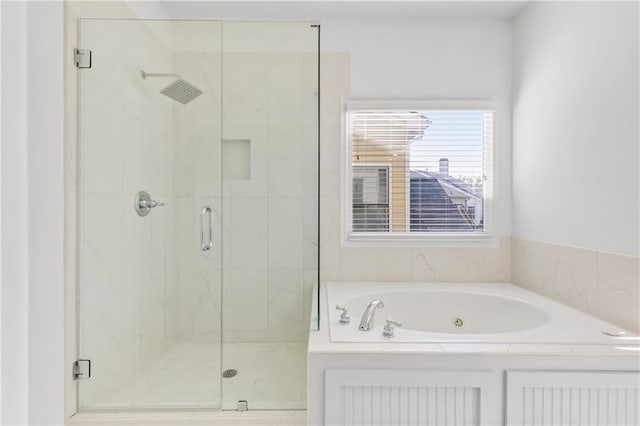 bathroom featuring a garden tub and a marble finish shower