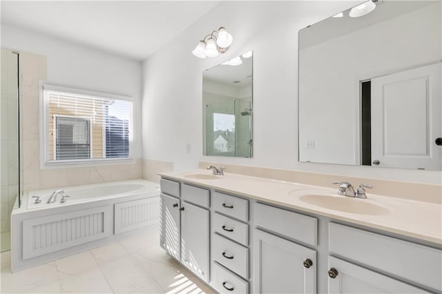 bathroom featuring a garden tub, marble finish floor, double vanity, and a sink