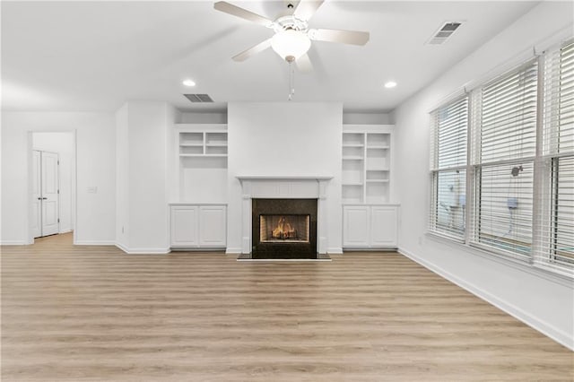 unfurnished living room with light wood finished floors, a fireplace with flush hearth, visible vents, and baseboards