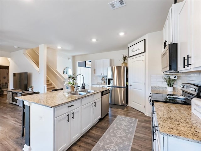 kitchen with white cabinetry, a center island with sink, stainless steel appliances, decorative backsplash, and sink