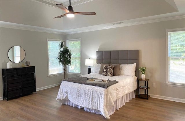 bedroom featuring wood finished floors, multiple windows, ornamental molding, and baseboards