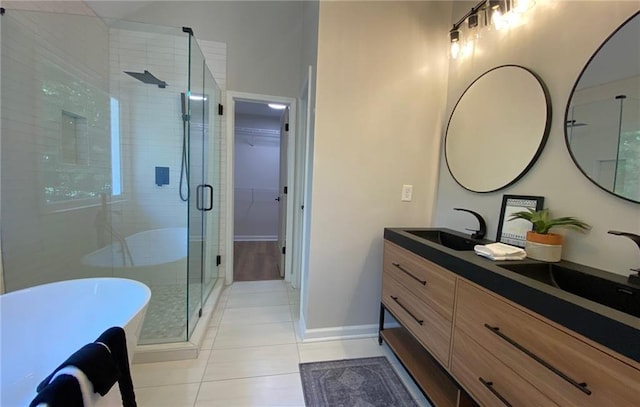 bathroom with a stall shower, double vanity, tile patterned flooring, a freestanding bath, and baseboards