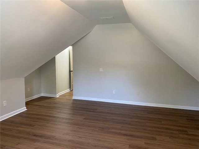 additional living space featuring baseboards, lofted ceiling, and dark wood-type flooring