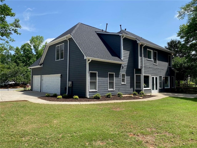 view of front of home featuring an attached garage, driveway, a front yard, and roof with shingles