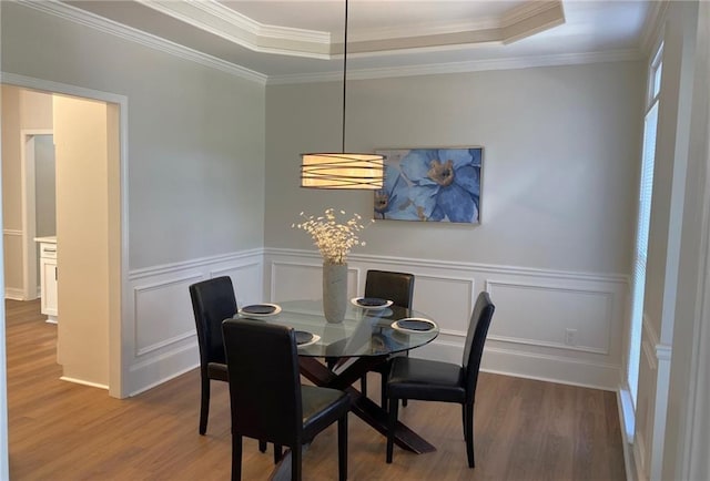 dining room with wood finished floors, a wainscoted wall, and ornamental molding