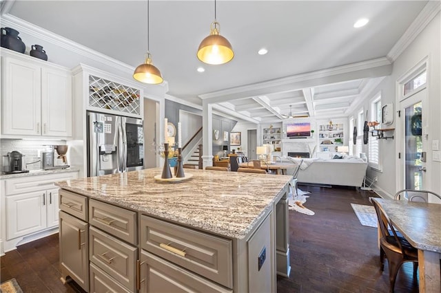 3111 Old Thompson Mill Rd, Buford, GA 30519 - kitchen featuring stainless steel fridge, a warm lit fireplace, ornamental molding, a kitchen island, and dark wood-type flooring