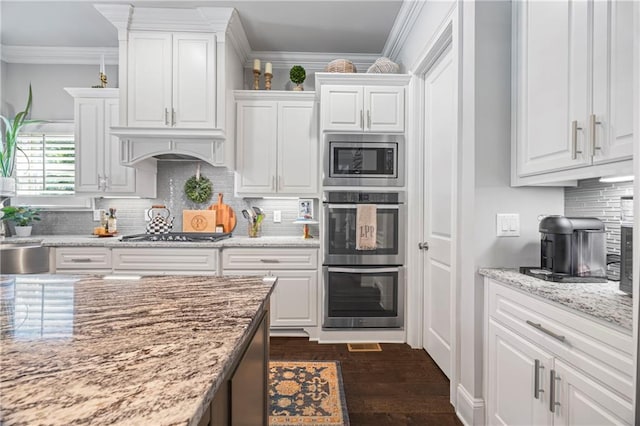 3111 Old Thompson Mill Rd, Buford, GA 30519 - kitchen with stainless steel appliances, white cabinets, crown molding, decorative backsplash, and light stone counters