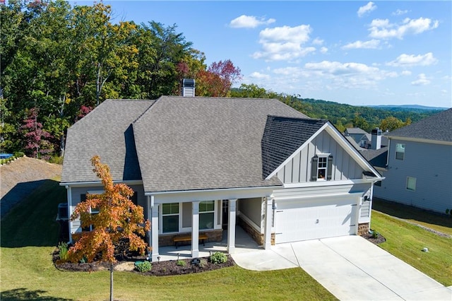 view of front of house featuring covered porch, a garage, and a front lawn