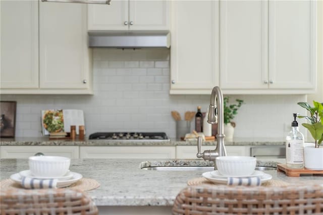 details with white cabinetry, light stone countertops, and backsplash