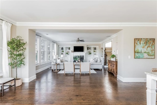 living room with built in features, ceiling fan, crown molding, and dark wood-type flooring