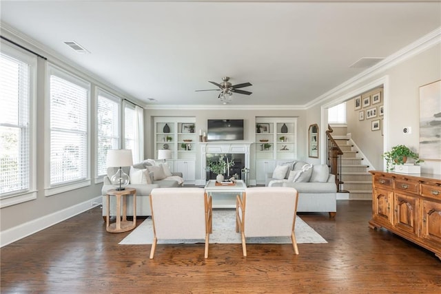 living room featuring built in shelves, plenty of natural light, ceiling fan, and ornamental molding