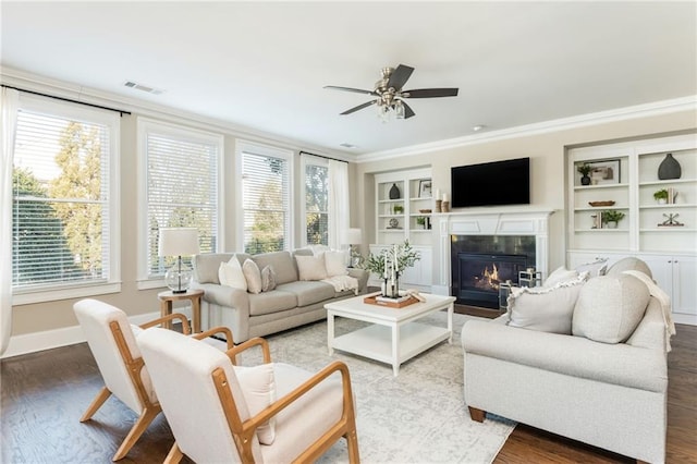 living room with hardwood / wood-style flooring, ceiling fan, built in shelves, and crown molding