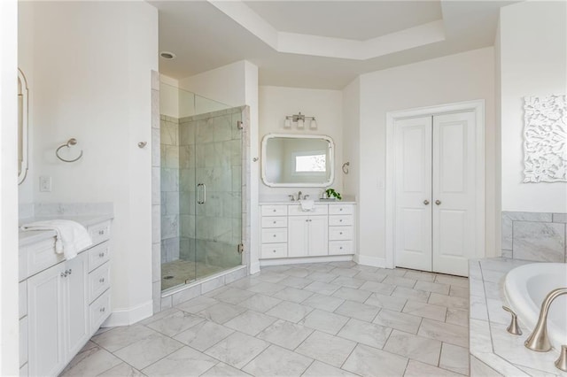 bathroom featuring vanity, a raised ceiling, and separate shower and tub