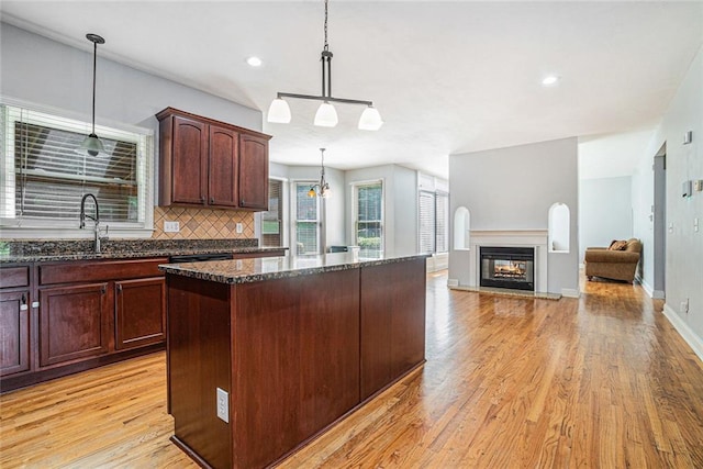 3641 Mountain Cove Rd, Snellville, GA 30039 - kitchen with a kitchen island, light wood finished floors, dark stone counters, decorative backsplash, and pendant lighting