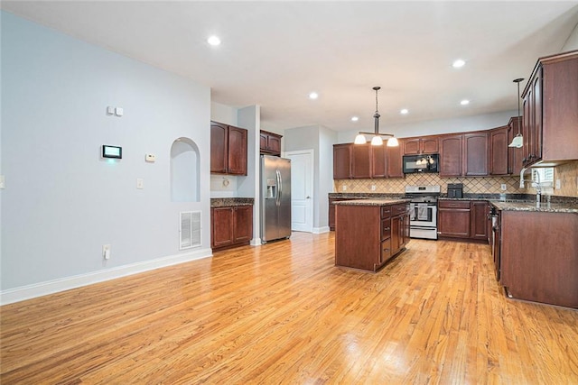 3641 Mountain Cove Rd, Snellville, GA 30039 - kitchen featuring appliances with stainless steel finishes, a center island, light wood-type flooring, tasteful backsplash, and baseboards