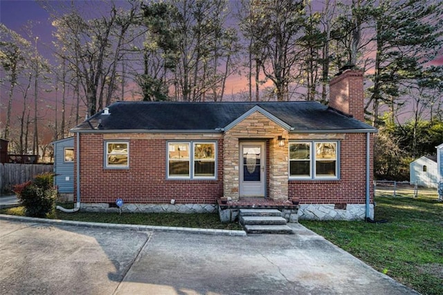 view of front of home featuring brick siding, crawl space, a chimney, and fence