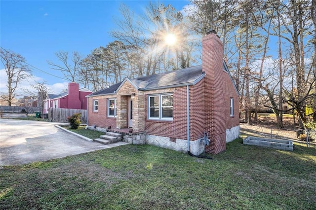 bungalow-style house with brick siding, a chimney, a front yard, crawl space, and fence