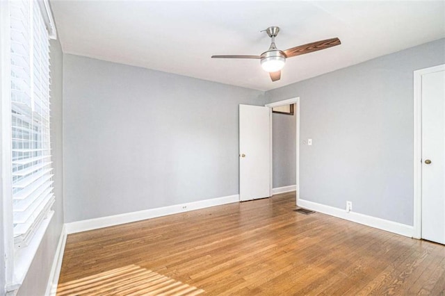 empty room with a ceiling fan, baseboards, and wood finished floors