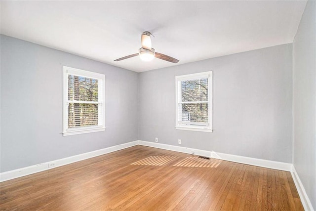 spare room with baseboards, light wood finished floors, a ceiling fan, and a healthy amount of sunlight